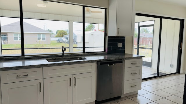 1942 SE Carvalho St, Port Saint Lucie, FL 34983 - kitchen with a sink, dishwasher, dark stone counters, light tile patterned floors, and backsplash