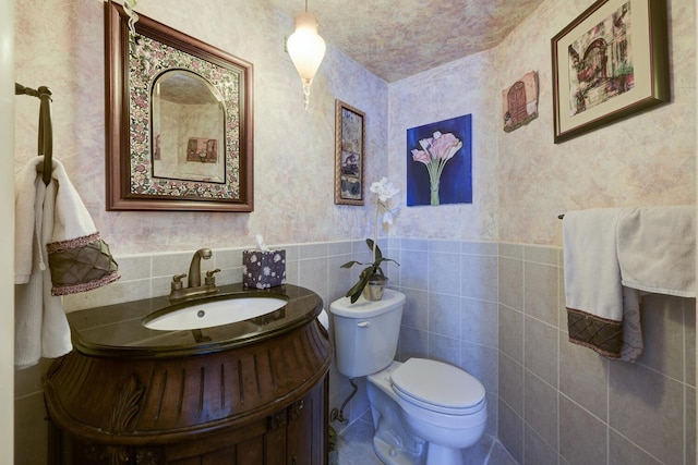 3800 Washington Rd Unit 1002, West Palm Beach, FL 33405 - bathroom with toilet, vanity, tile walls, and wainscoting