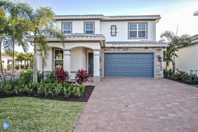 12546 Triumph Ln, Palm Beach Gardens, FL 33412 - view of front of property with a tiled roof, decorative driveway, an attached garage, stone siding, and stucco siding