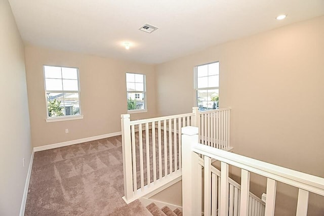 12546 Triumph Ln, Palm Beach Gardens, FL 33412 - hallway featuring plenty of natural light, carpet, visible vents, and an upstairs landing