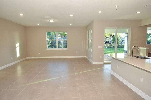 12546 Triumph Ln, Palm Beach Gardens, FL 33412 - unfurnished living room with a sink, light tile patterned floors, recessed lighting, and a healthy amount of sunlight