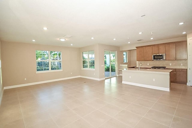 12546 Triumph Ln, Palm Beach Gardens, FL 33412 - kitchen featuring backsplash, stainless steel microwave, open floor plan, recessed lighting, and an island with sink