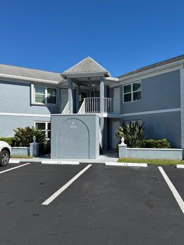 view of front of home with uncovered parking, stucco siding, and a balcony