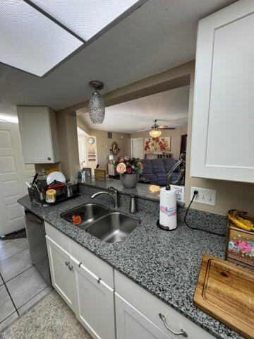 kitchen featuring light tile patterned flooring, ceiling fan, white cabinets, a sink, and dishwasher