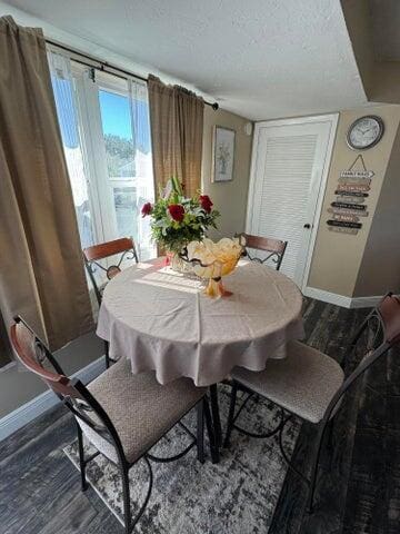 dining room with baseboards, a textured ceiling, and wood finished floors