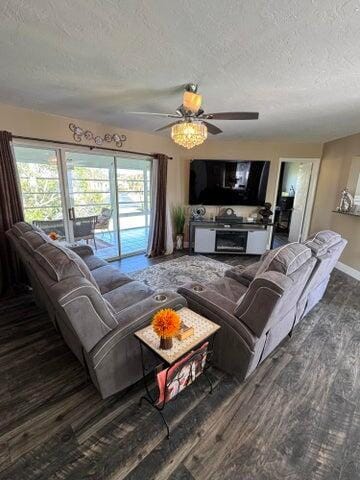 living area featuring baseboards, a ceiling fan, a textured ceiling, and wood finished floors