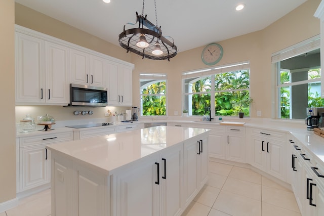 4510 Island Reef Dr, Wellington, FL 33449 - kitchen with black electric stovetop, a center island, stainless steel microwave, a sink, and light tile patterned floors