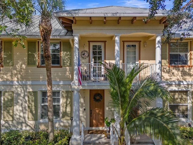 view of front of house with a balcony, a standing seam roof, and metal roof