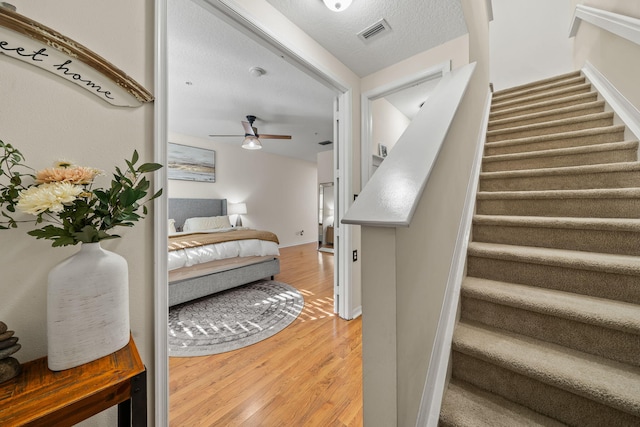 stairs with wood finished floors, a ceiling fan, and baseboards
