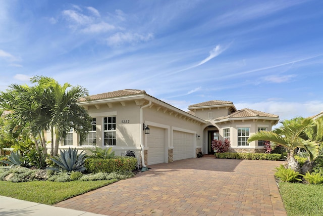 9252 SW Miracoli Way, Port Saint Lucie, FL 34987 - mediterranean / spanish-style home with stone siding, stucco siding, an attached garage, and decorative driveway
