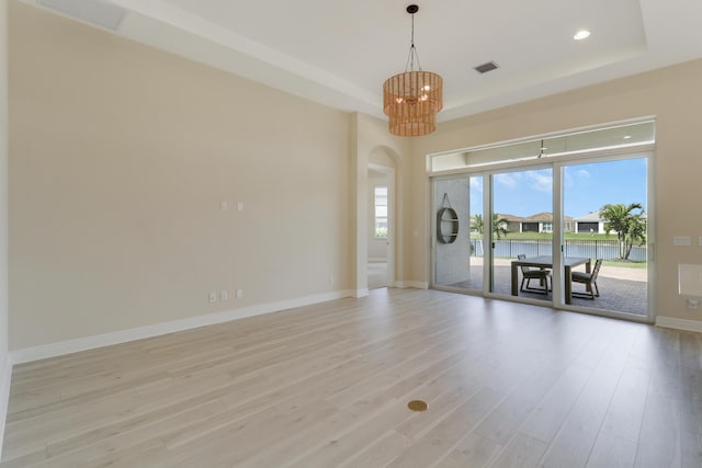 9252 SW Miracoli Way, Port Saint Lucie, FL 34987 - empty room with visible vents, a chandelier, light wood-style flooring, a tray ceiling, and baseboards