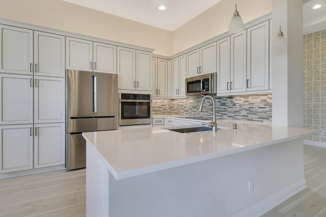 9252 SW Miracoli Way, Port Saint Lucie, FL 34987 - kitchen featuring a sink, a peninsula, decorative backsplash, stainless steel appliances, and light wood-type flooring