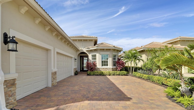 9252 SW Miracoli Way, Port Saint Lucie, FL 34987 - view of front of home with an attached garage, stucco siding, decorative driveway, and stone siding