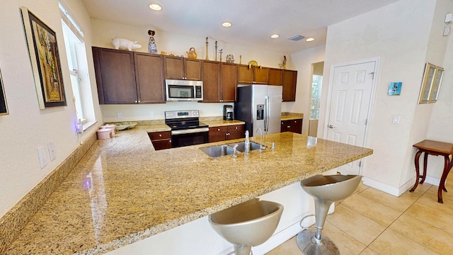 2323 NW Padova St, Port Saint Lucie, FL 34986 - kitchen with light stone counters, a sink, appliances with stainless steel finishes, and a peninsula