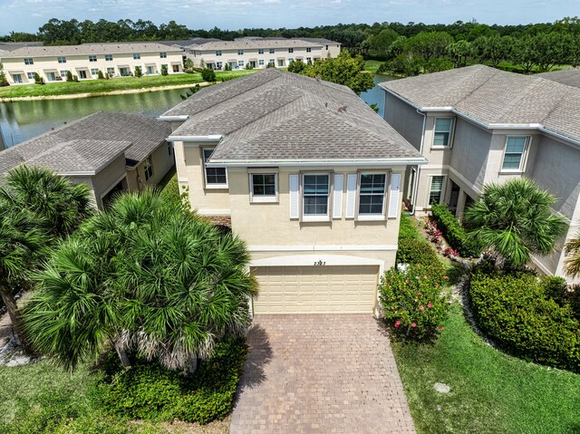 2323 NW Padova St, Port Saint Lucie, FL 34986 - view of front of property with roof with shingles, decorative driveway, a water view, an attached garage, and stucco siding
