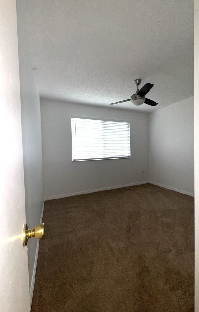 spare room featuring baseboards, ceiling fan, and carpet