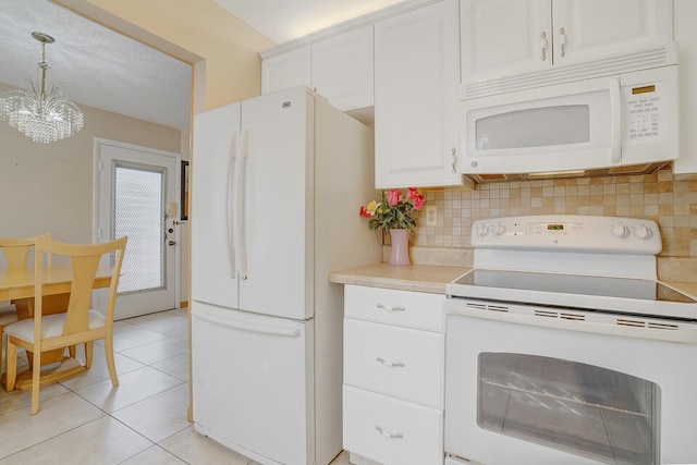 kitchen with white appliances, decorative backsplash, a chandelier, and white cabinetry