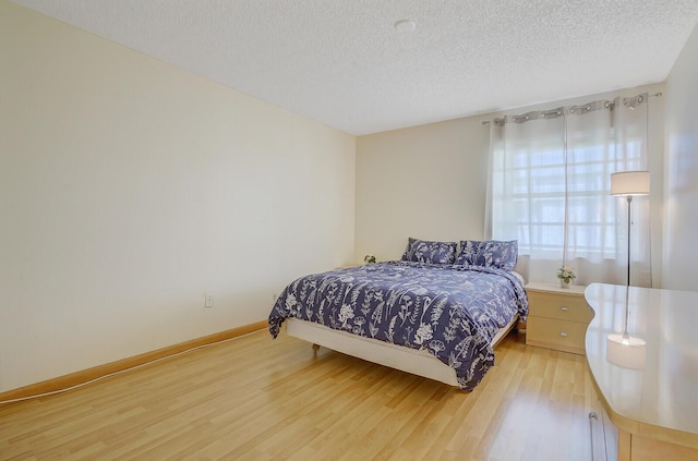bedroom featuring wood finished floors, a textured ceiling, and baseboards