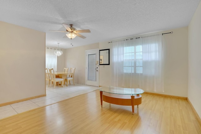 living room featuring wood finished floors, healthy amount of natural light, ceiling fan, a textured ceiling, and baseboards