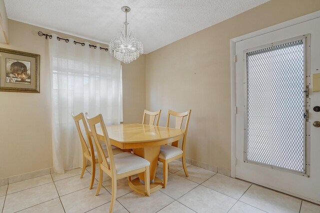 dining area featuring a chandelier, light tile patterned floors, and baseboards