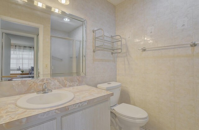 full bathroom featuring a stall shower, vanity, toilet, tile walls, and backsplash