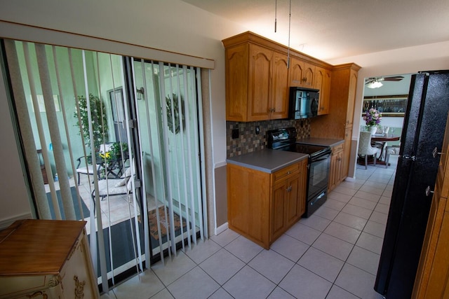 kitchen featuring brown cabinetry, ceiling fan, light tile patterned floors, backsplash, and black appliances