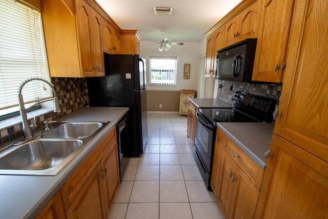 kitchen with a sink, brown cabinetry, a ceiling fan, backsplash, and black appliances