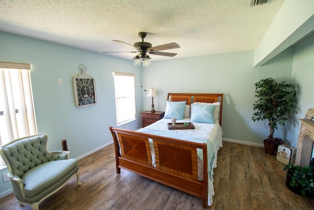 bedroom featuring baseboards, a ceiling fan, a textured ceiling, and wood finished floors