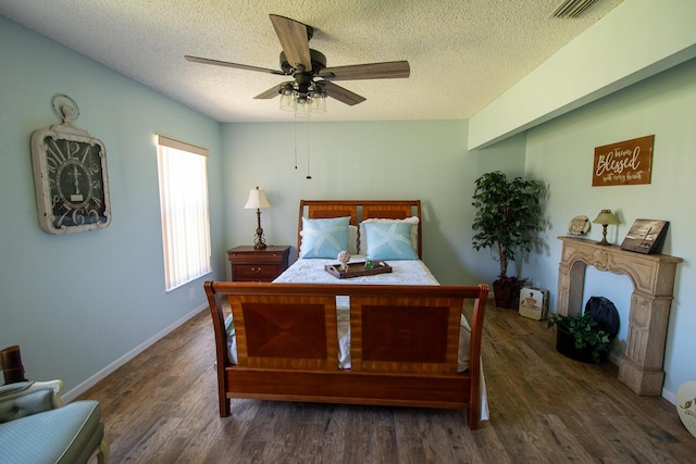 bedroom with a ceiling fan, a textured ceiling, visible vents, wood finished floors, and baseboards