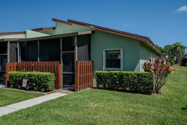 view of home's exterior with a sunroom, stucco siding, and a yard