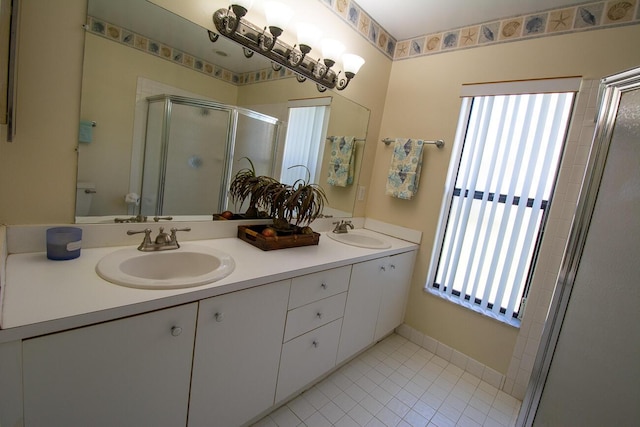 bathroom with a sink, tile patterned flooring, a shower stall, and double vanity