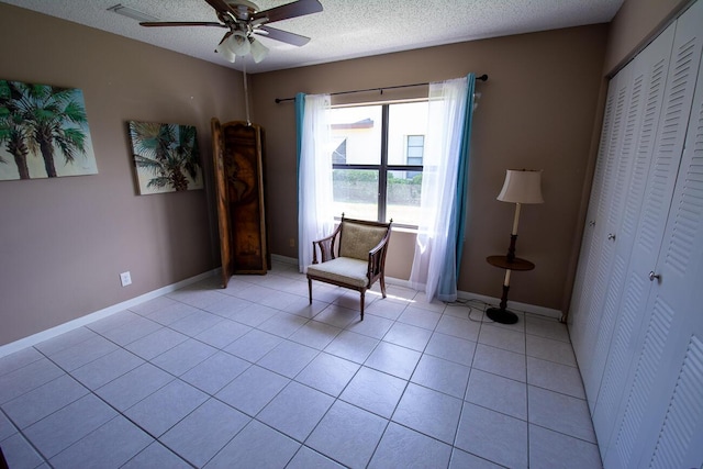 living area featuring light tile patterned floors, baseboards, and a ceiling fan