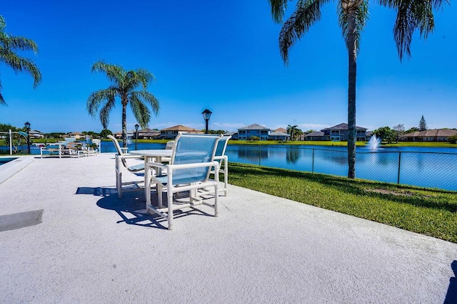 view of patio with a water view, fence, and a residential view