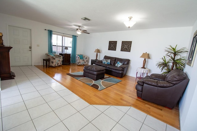 living area featuring light tile patterned floors, a ceiling fan, and visible vents