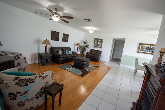 living room featuring light tile patterned floors, baseboards, ceiling fan, and visible vents