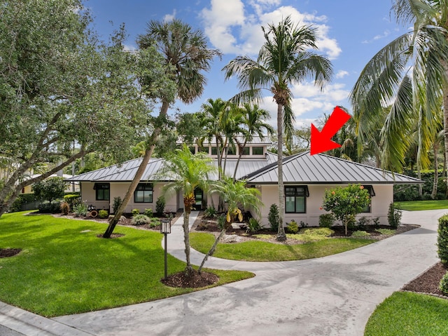 121 Hillcrest Dr, Sewalls Point, FL 34996 - view of front facade featuring a standing seam roof, metal roof, stucco siding, a front lawn, and concrete driveway