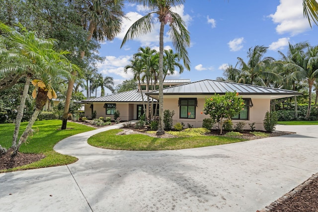 121 Hillcrest Dr, Sewalls Point, FL 34996 - view of front of house featuring a standing seam roof, stucco siding, metal roof, a front yard, and concrete driveway