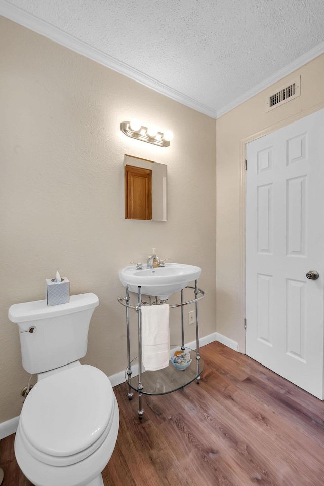 3205 Tennessee Ave, Fort Pierce, FL 34950 - half bath featuring crown molding, toilet, a textured ceiling, wood finished floors, and visible vents
