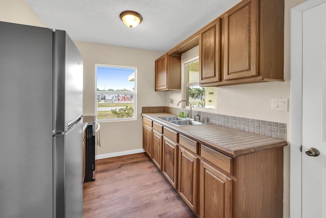 3205 Tennessee Ave, Fort Pierce, FL 34950 - kitchen with brown cabinets, a sink, light wood finished floors, light countertops, and freestanding refrigerator