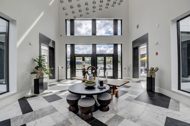 entrance foyer with visible vents, marble finish floor, a towering ceiling, baseboards, and french doors