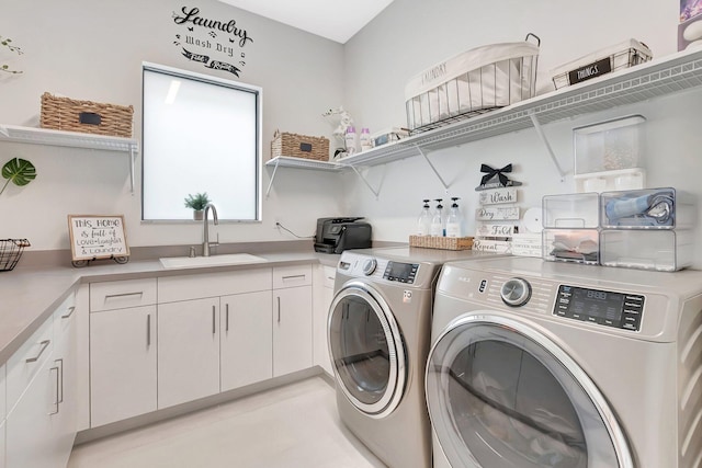 clothes washing area with a sink, cabinet space, and washer and clothes dryer