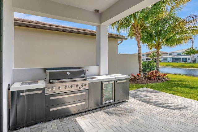 view of patio / terrace featuring a sink, a grill, area for grilling, wine cooler, and a water view