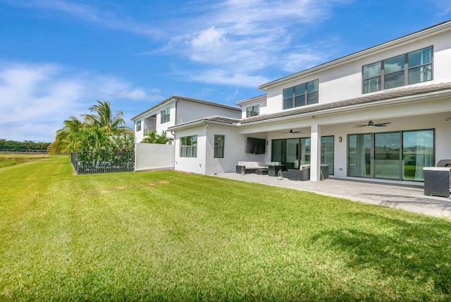 back of property with ceiling fan, an outdoor living space, a lawn, a patio area, and stucco siding
