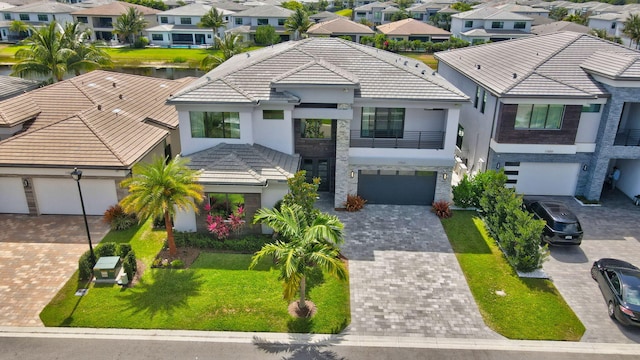view of front of home featuring a balcony, decorative driveway, stucco siding, a residential view, and a tile roof