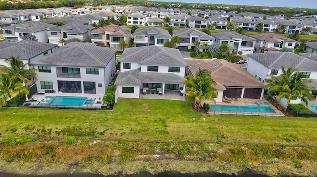 back of property with a residential view, a fenced in pool, a patio area, a tiled roof, and a yard