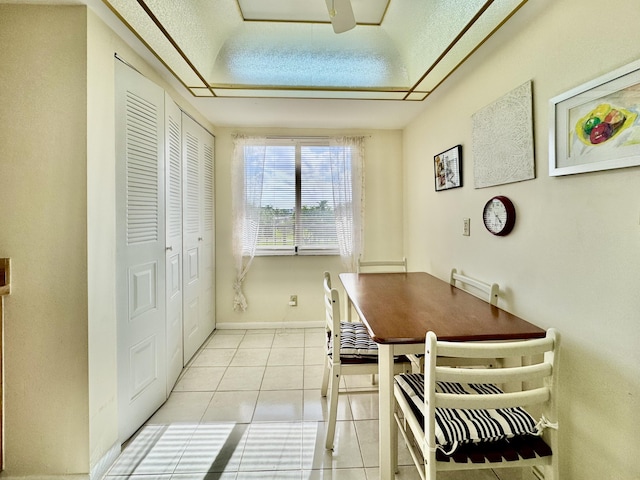 dining room with baseboards, a raised ceiling, and light tile patterned flooring