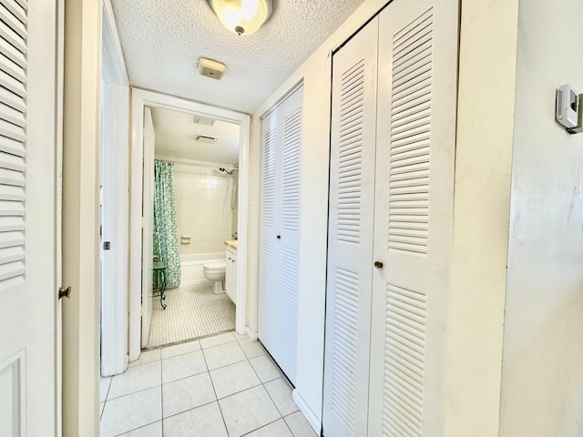 corridor featuring a textured ceiling and light tile patterned floors