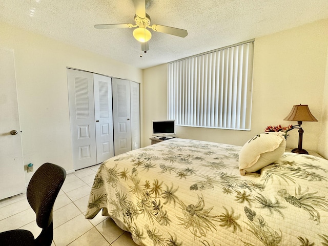 bedroom featuring light tile patterned floors, ceiling fan, a closet, and a textured ceiling