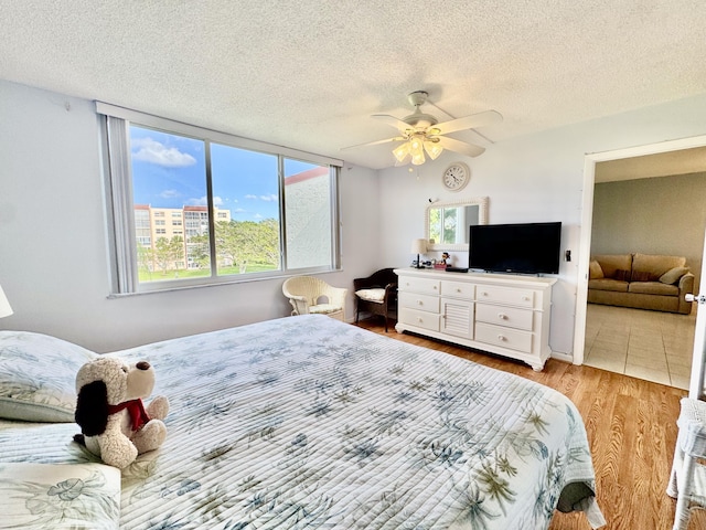 bedroom with ceiling fan, multiple windows, a textured ceiling, and wood finished floors