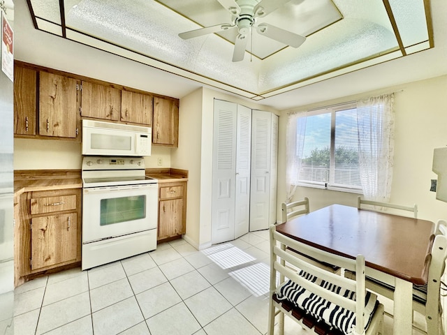 kitchen with white appliances, light countertops, brown cabinets, a ceiling fan, and light tile patterned floors